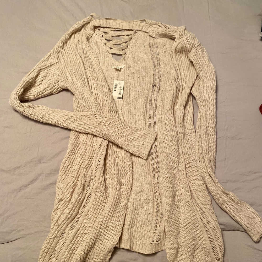 A beige knitted cardigan with a criss cross back